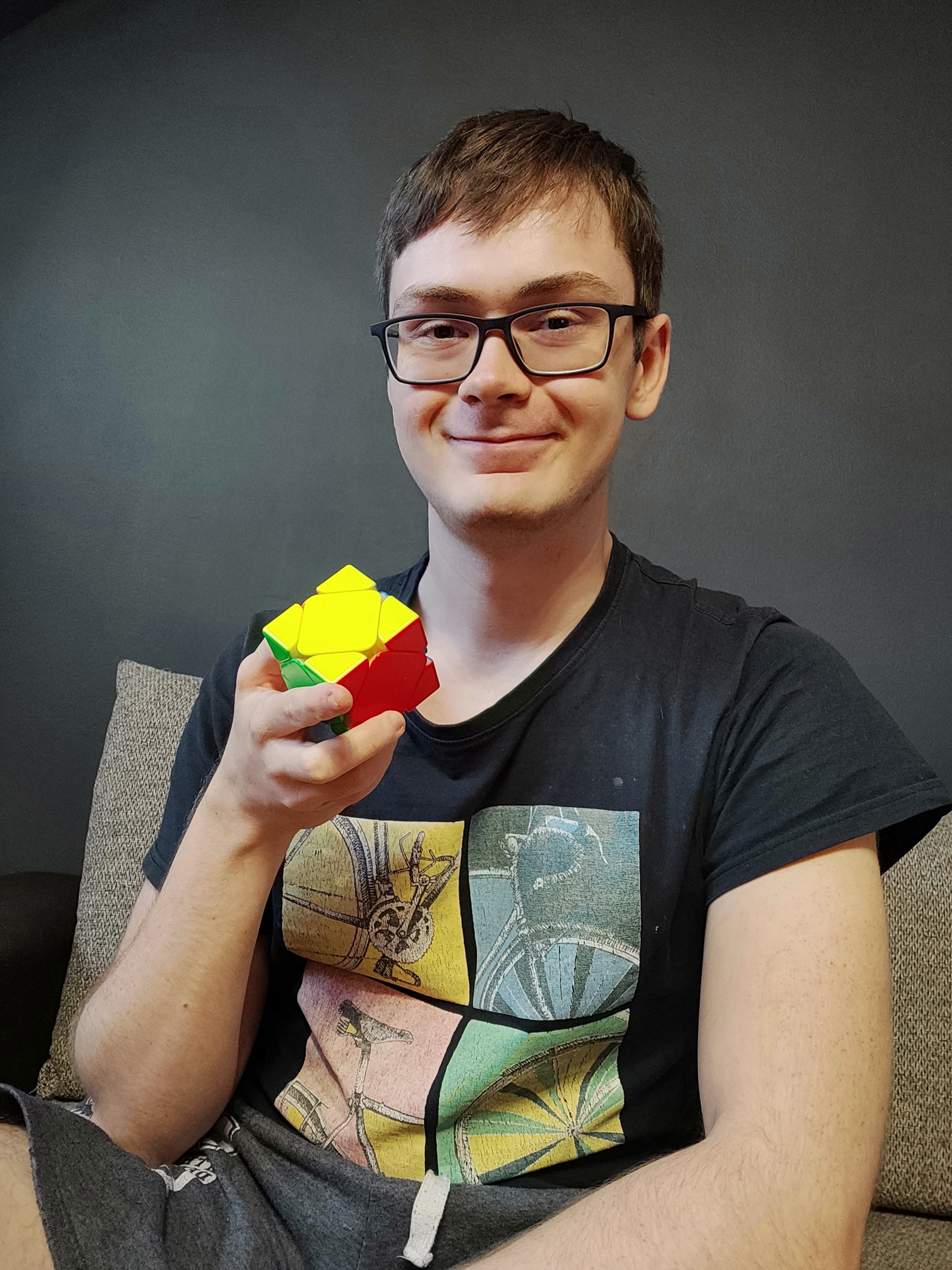 Mężczyzna trzyma w ręcę ułożoną kostkę Skewb.